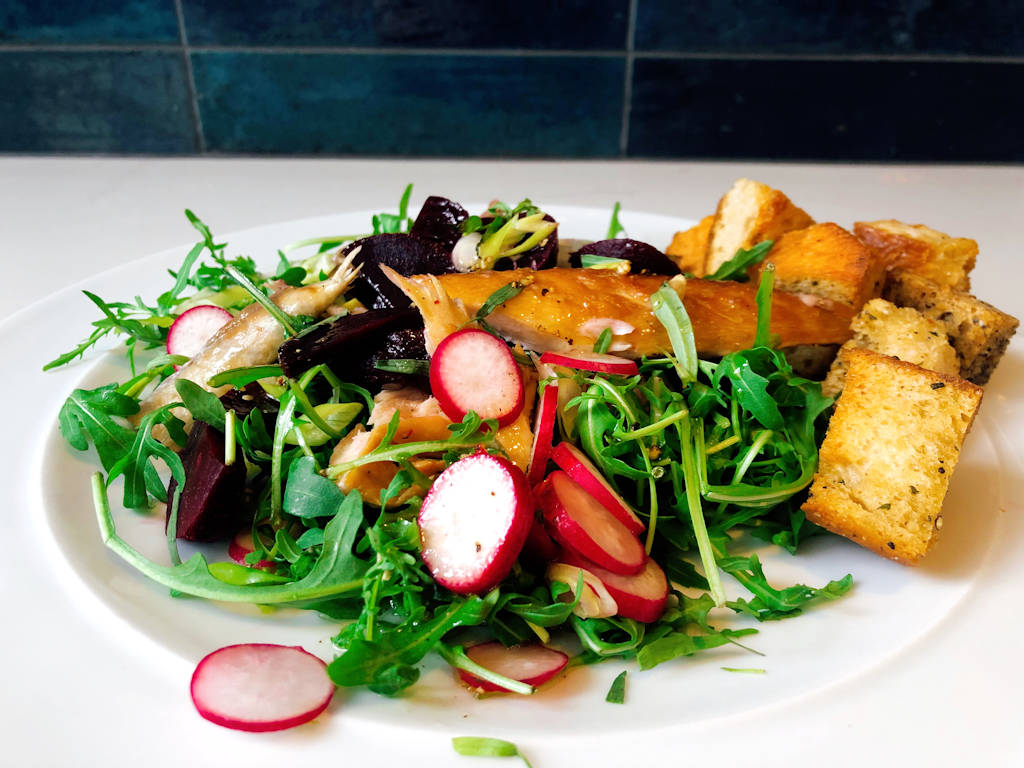 Plate of beetroot and mackerel salad on white plate