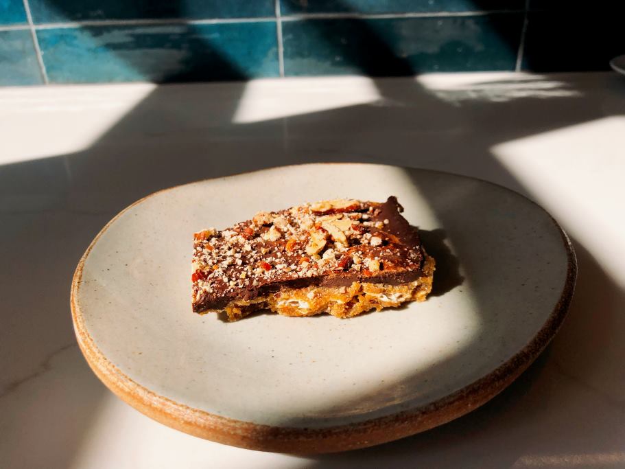 A plate with a piece of Toffee Bark with Salted Pecans