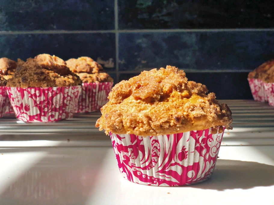 Rhubarb muffin in pink muffin case in front of cooling rack