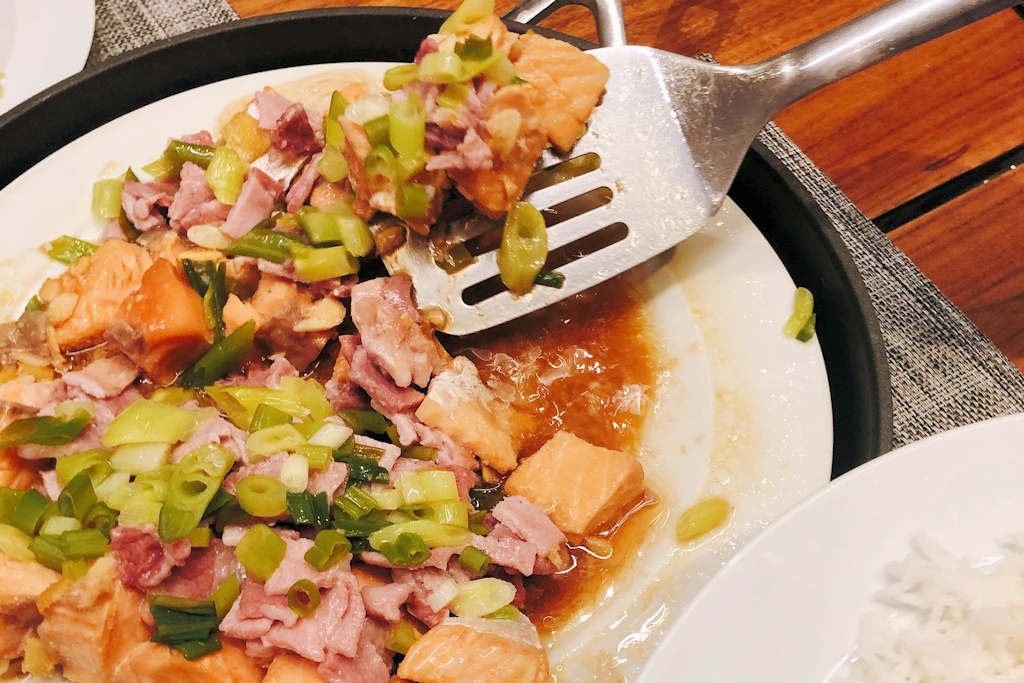 Plate of Steamed Salmon with bacon and green onions with spatula