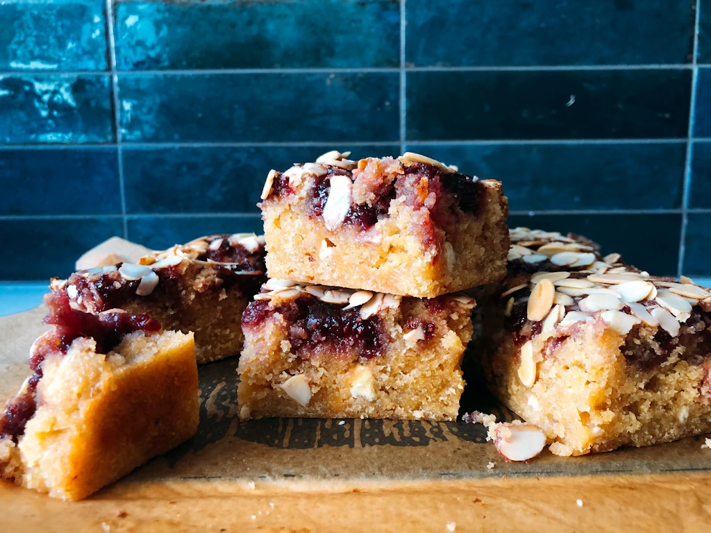 Plate full of bakewell blondies with blue tile background.