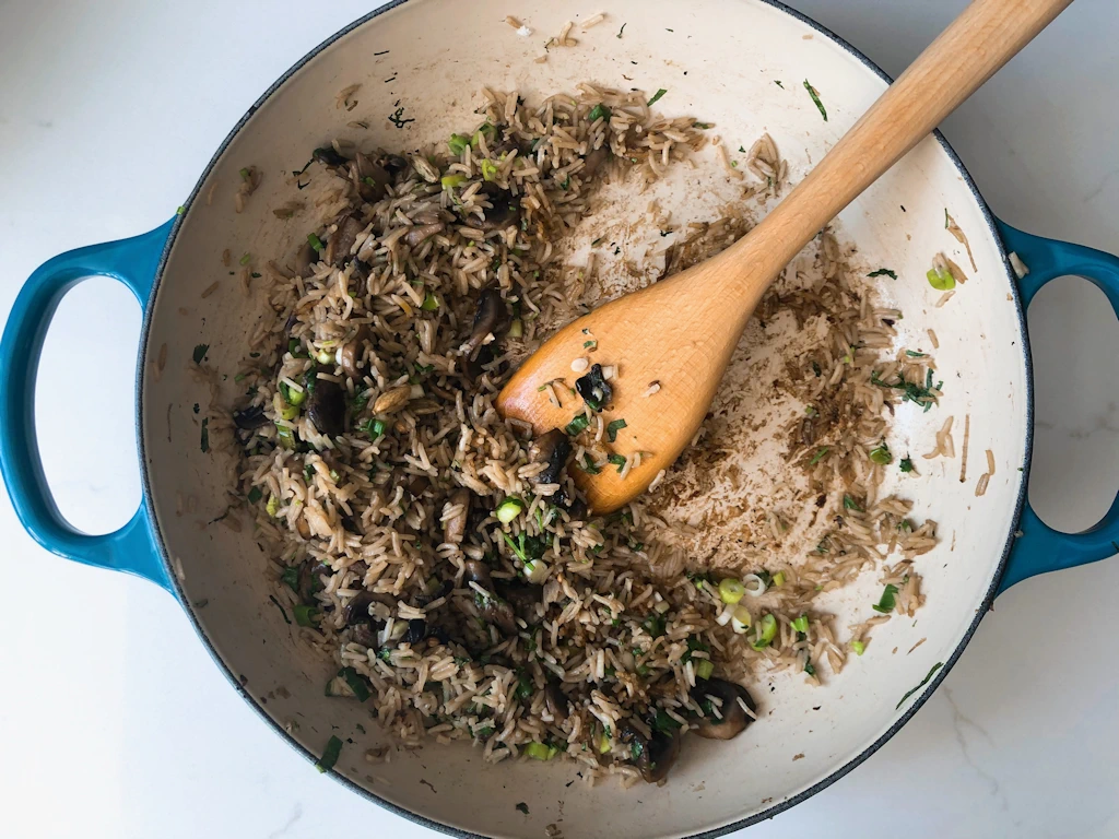 Pan of mushroom pilau rice with a wooden spoon