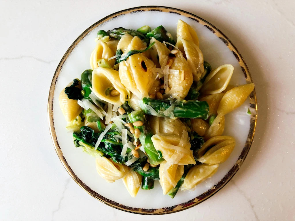 Gold rimmed plate of pasta primavera with asparagus