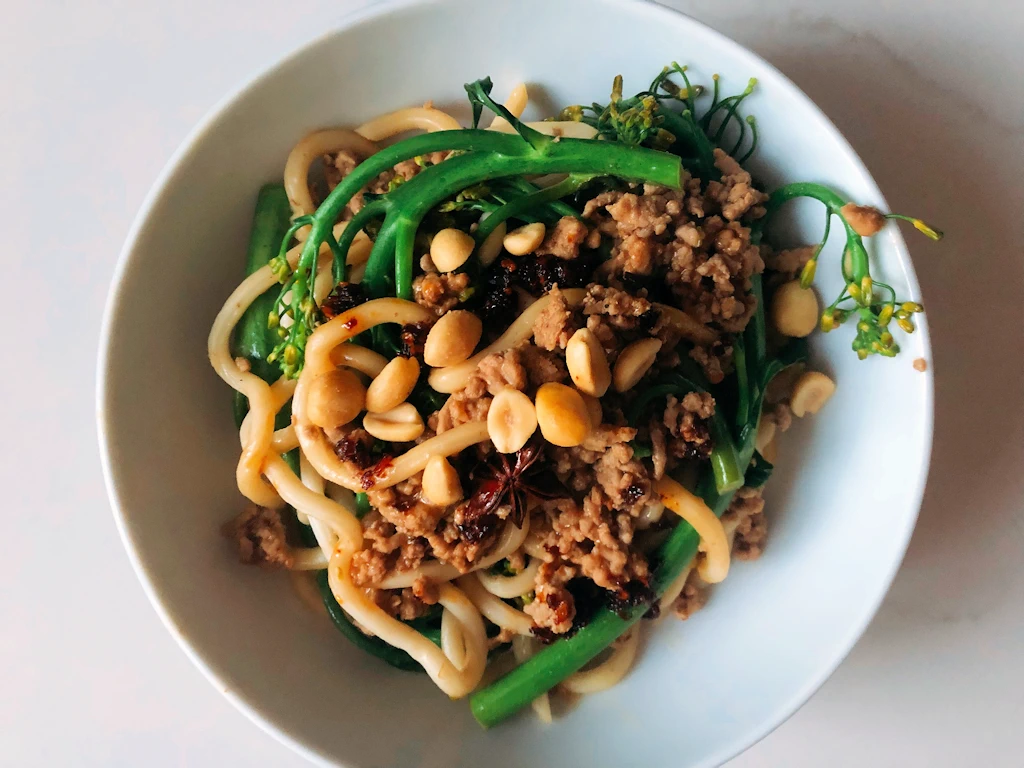 Bowl of Sichuan pork and peanut noodles with broccoli